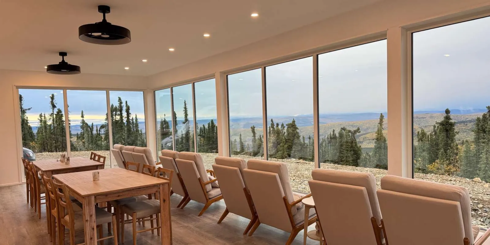 Interior lounge seating facing the floor-to-ceiling windows of the Aurora Glass House by day