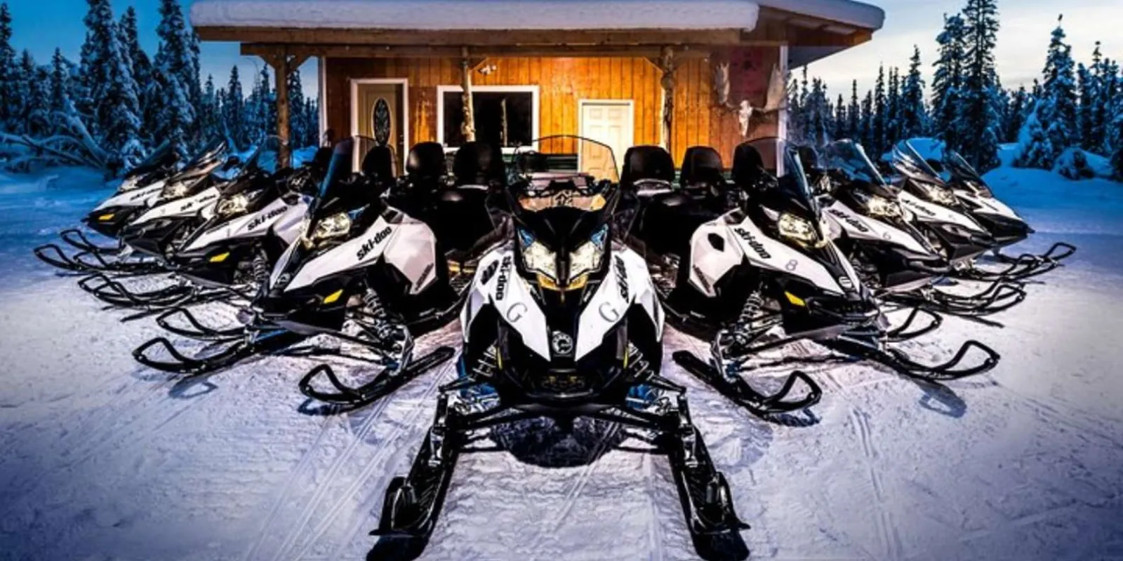 Row of touring snowmobiles parked in front of the operator's log lodge in North Pole, Alaska