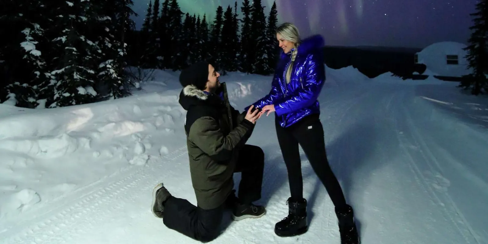 Marriage proposal captured under purple and green aurora with a dome-shaped viewing structure in the background